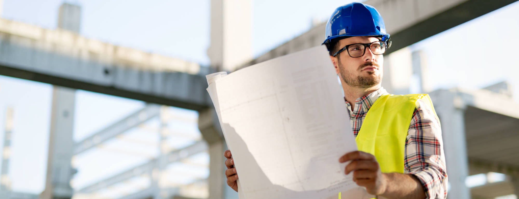 Un ouvrier lit un plan sur un chantier